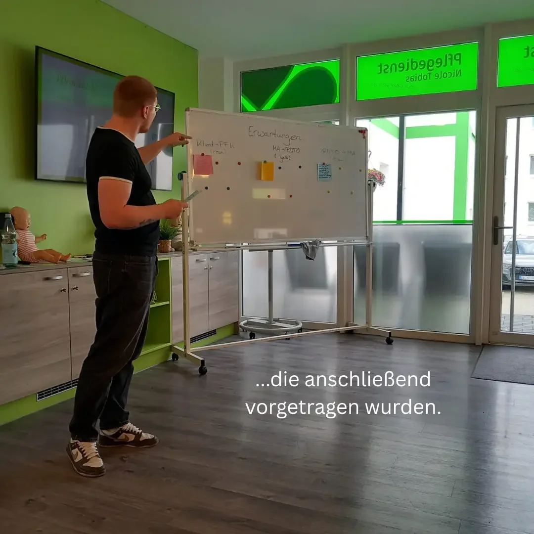 Mann vor einem Whiteboard mit der Aufschrift „Erwartungen“ und Haftnotizen in einem Raum mit grünen Wänden.