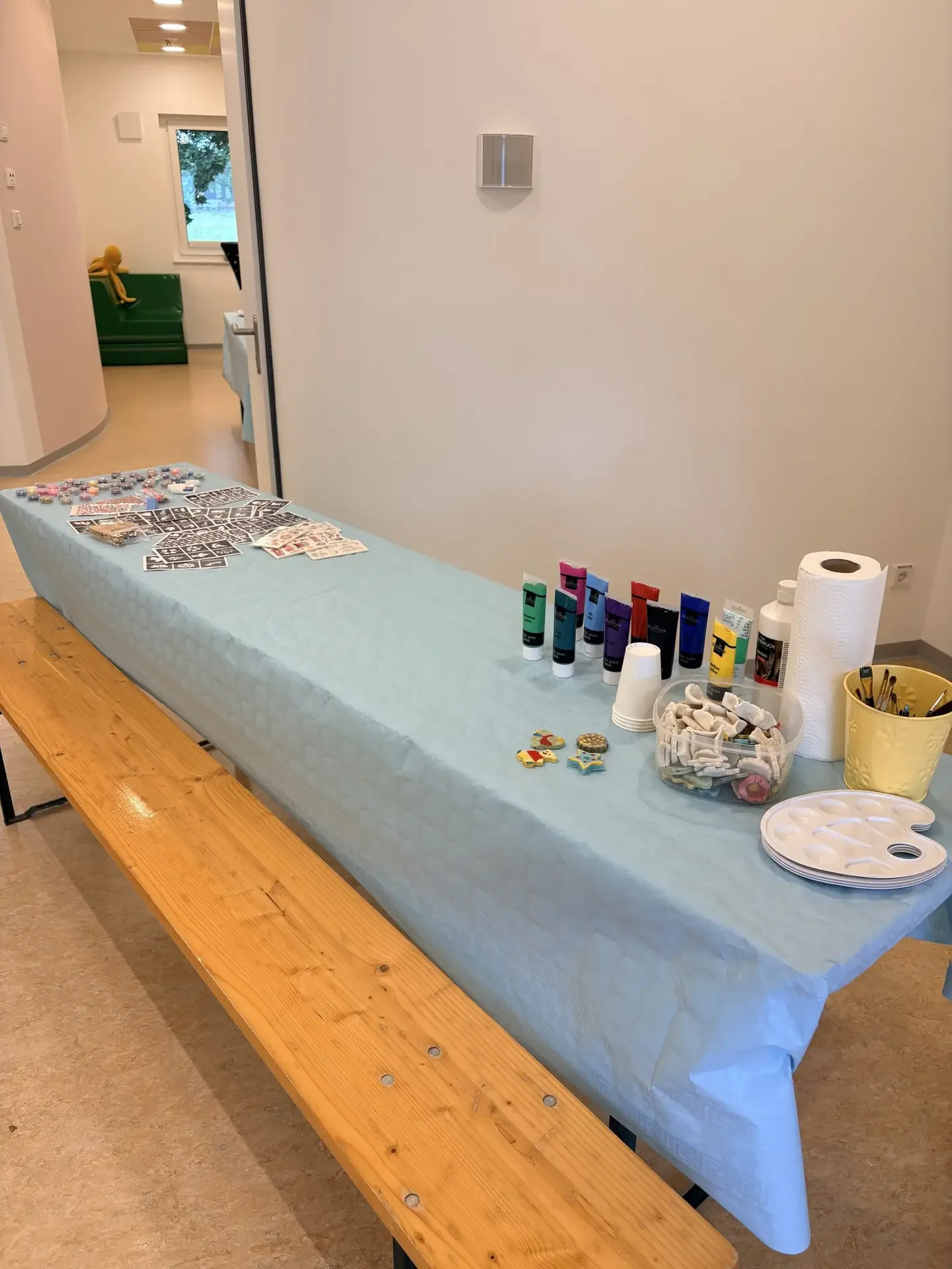 Basteltisch mit Farben, Pinseln und Malpapier auf blauer Tischdecke